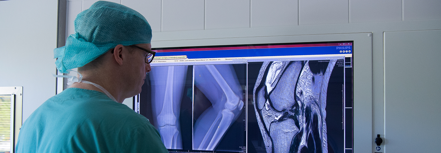 Chefarzt Doktor Götz betrachtet die Röntgenaufnahme eines Knies
